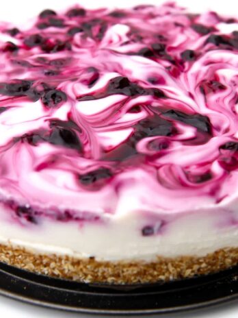 A vegan blueberry cheesecake with blueberry sauce swirled into it.