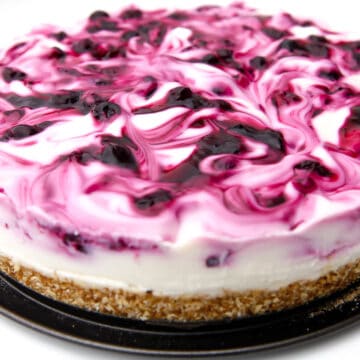 A vegan blueberry cheesecake with blueberry sauce swirled into it.