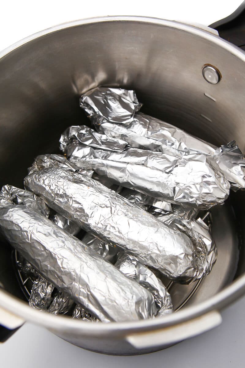 Seitan hot dogs wrapped in foil in a pressure cooker before steaming them to cook the wheat gluten.