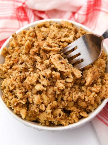 A bowl of vegan tuna made from soy protein in a white bowl with a red and white tea towel.