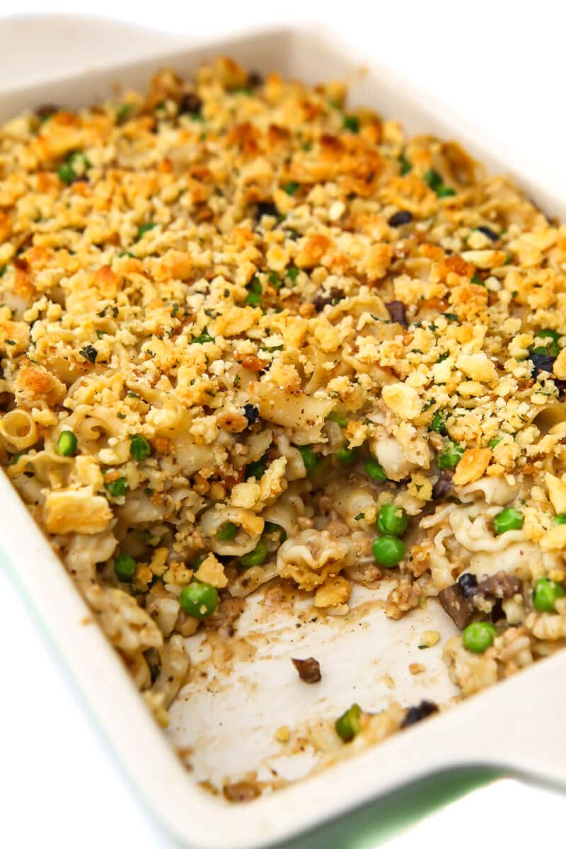 A vegan tuna casserole in a baking dish with a serving taken out of it.