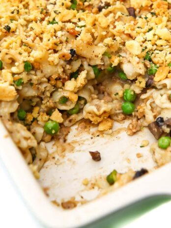 A close up of a vegan tuna casserole in a baking dish with a serving taken out of it.