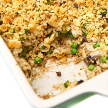 A close up of a vegan tuna casserole in a baking dish with a serving taken out of it.