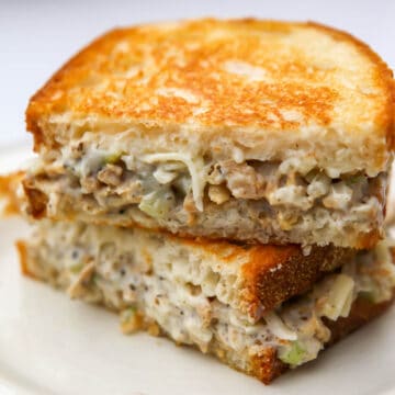 A close up of a vegan tuna sandwich on a white plate.
