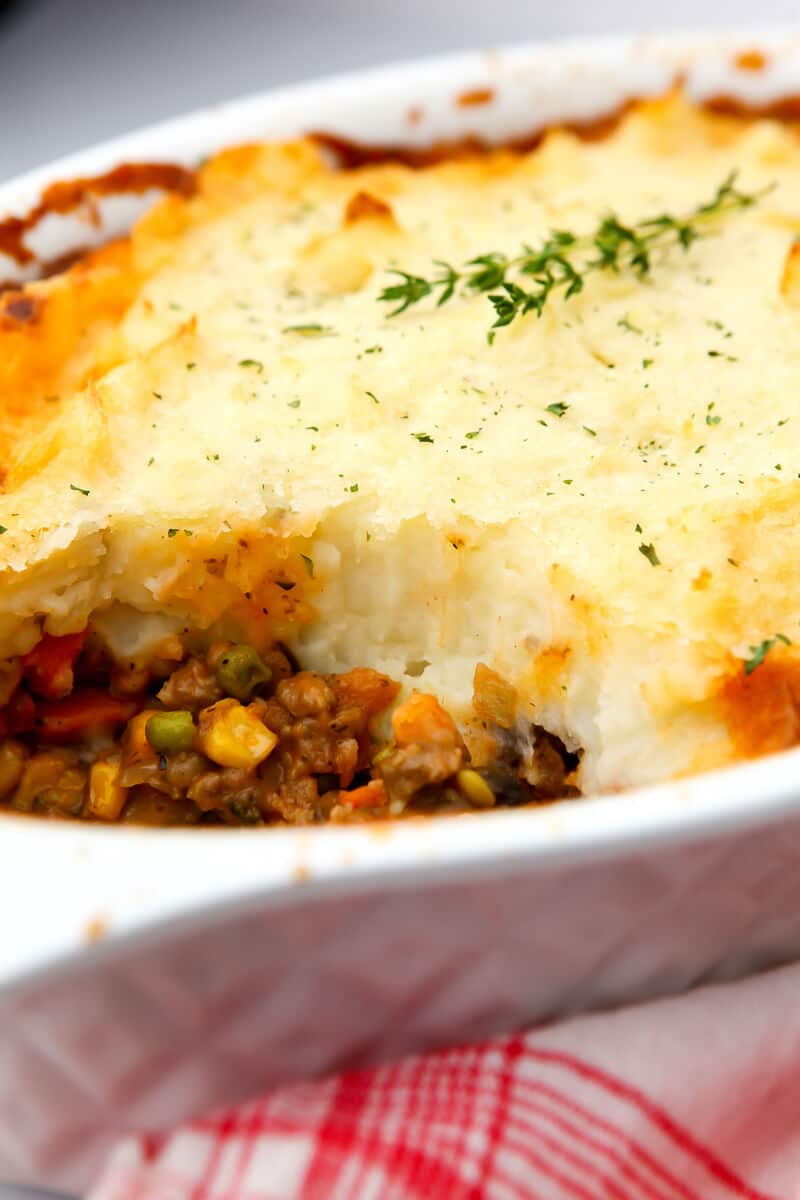 A dish of vegan shepherd's pie from the side with a thick layer of golden mashed potatoes on top.