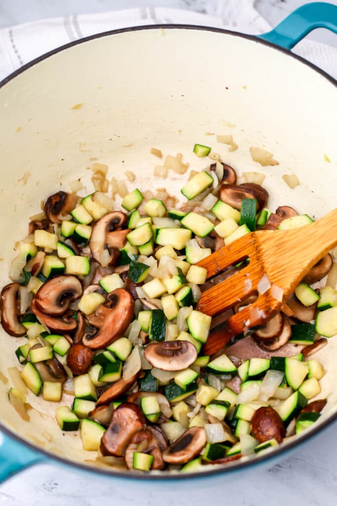 Onions, mushrooms and zucchini sauteing in a large pot to make vegan green chile stew.