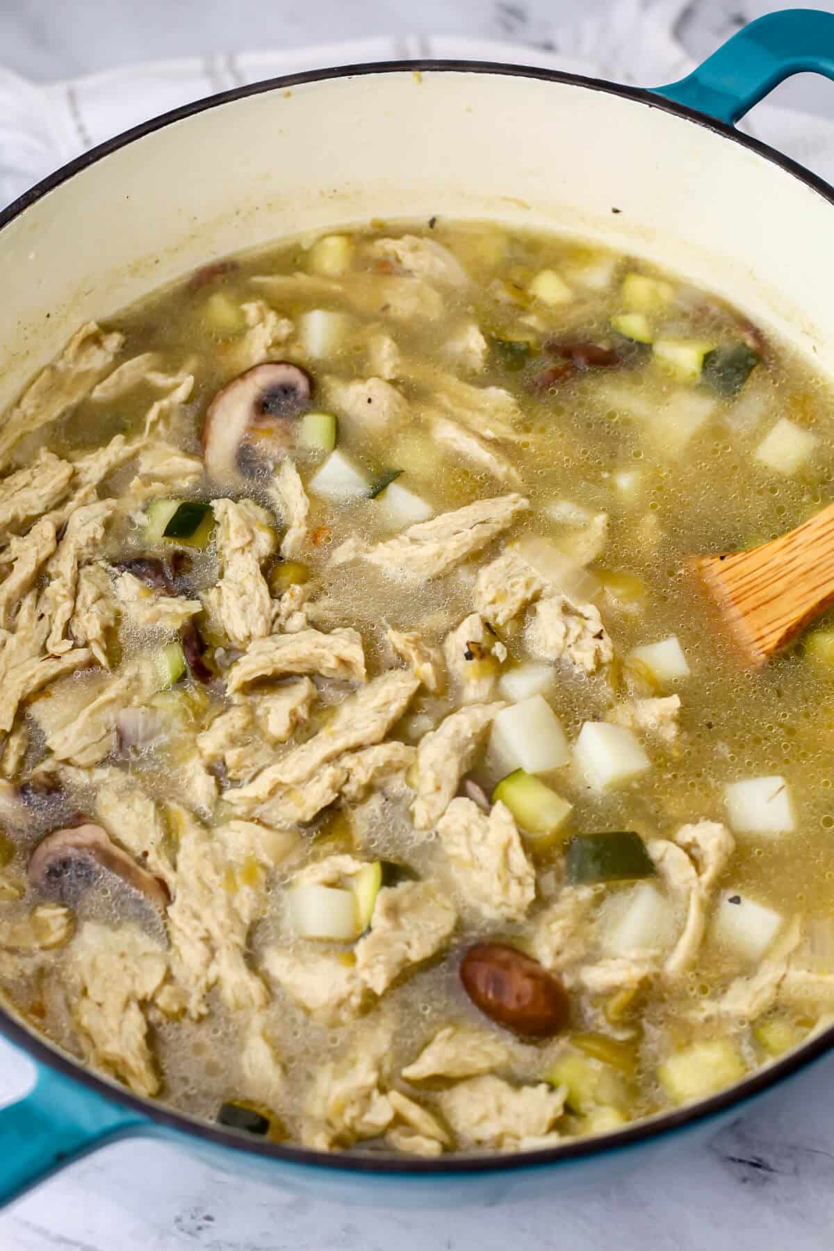 Vegan shredded chicken added to a pot of green chile stew.