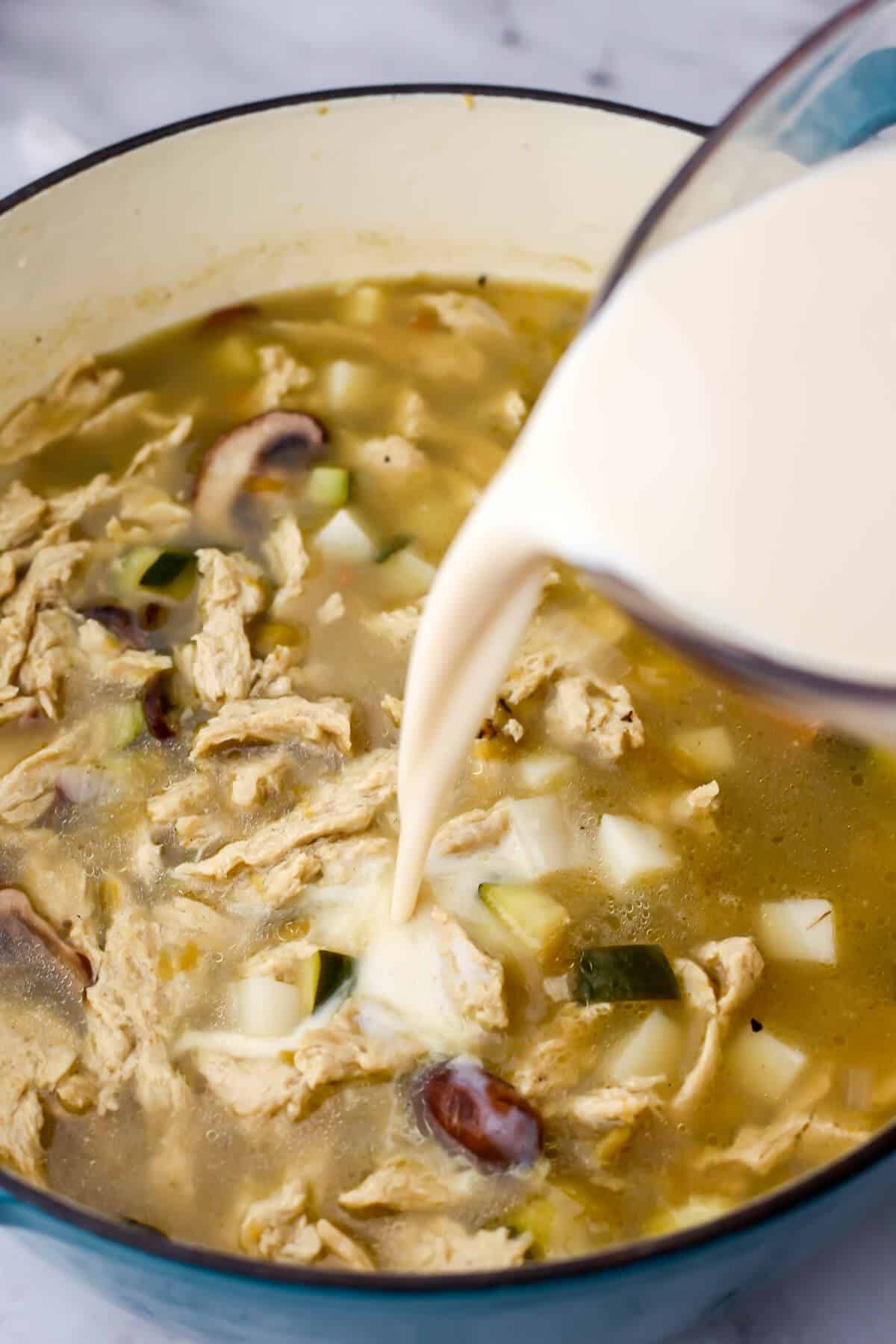Plant based milk being poured into dairy-free green chile stew.