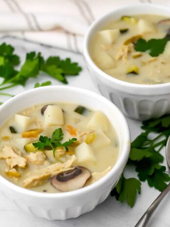 Two bowls of New Mexican style green chile stew made vegan with a spoon beside it and parsley around it.