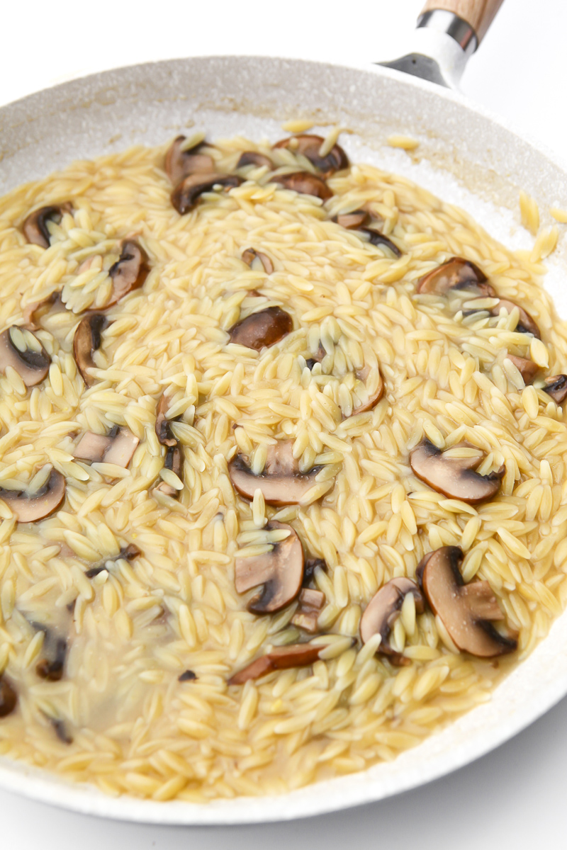 Broth added to the garlic, mushrooms, and orzo.