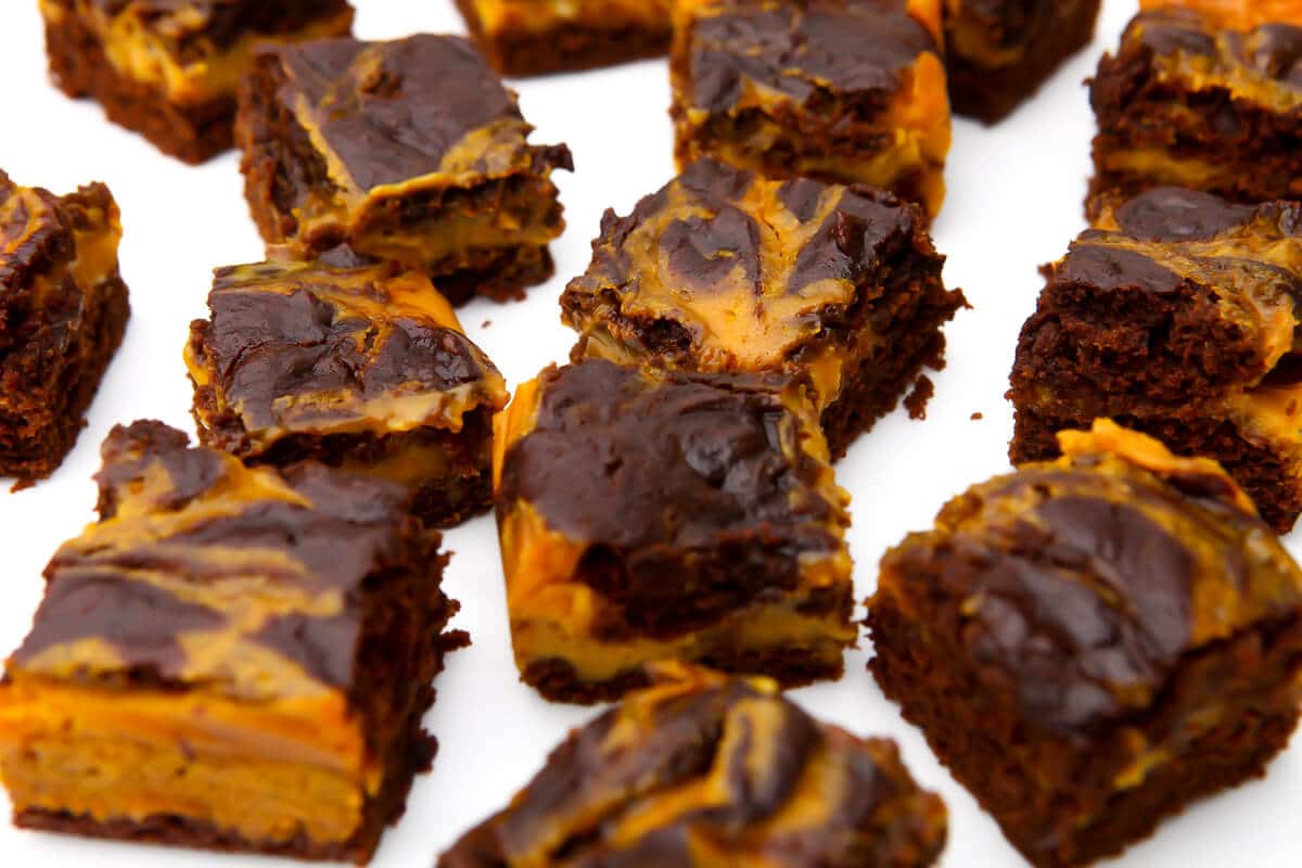 Vegan brownies with pumpkin swirled into them on a white counter top.