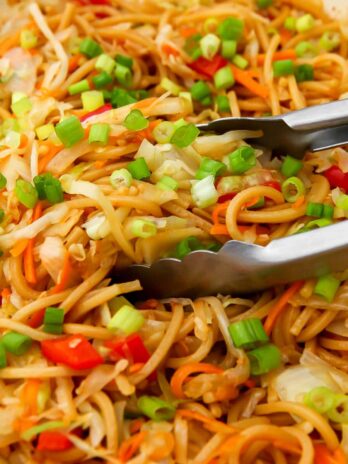 A close up of vegan Hakka noodles being stirred with tongs.