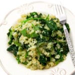 Riced cauliflower risotto with spinach on a white plate with a fork on the side.