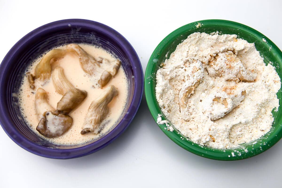 Two shallow bowls next to each other.  One bowl filled with the milk solution and one filled with the dry breading and seasonings to make vegan fried oyster mushrooms.