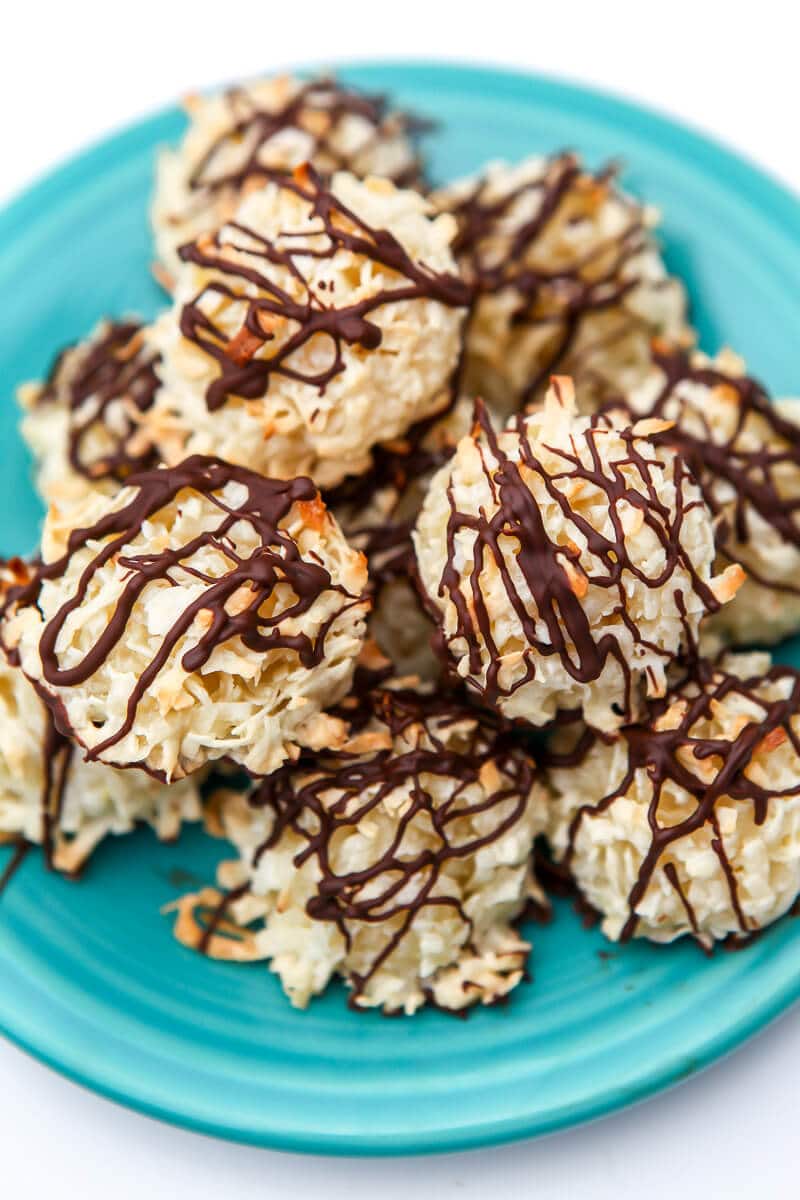 A top view of a plate of dairy-free coconut macaroon cookies with chocolate drizzle on top of them.