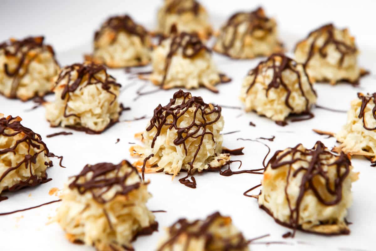 Vegan coconut macaroons on a piece of parchment paper drizzled in chocolate.