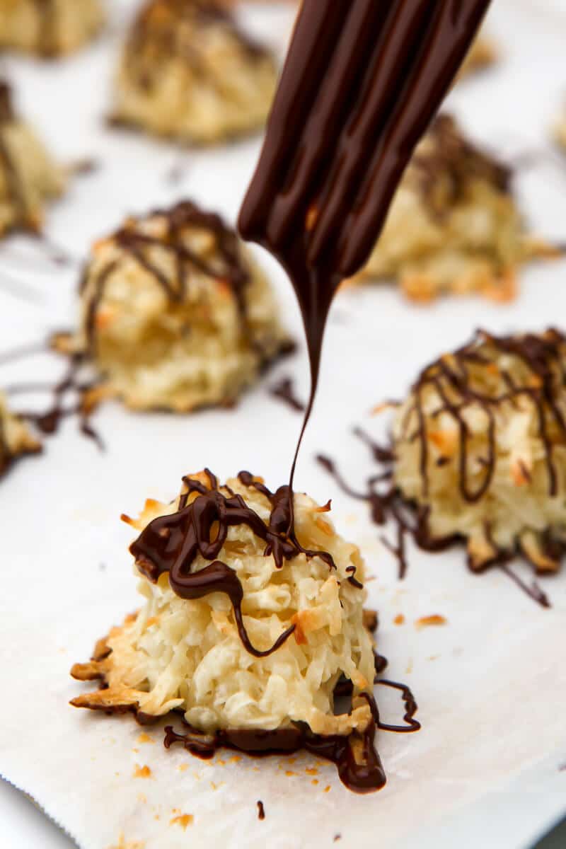A coconut macaroon being drizzled with melted vegan chocolate.