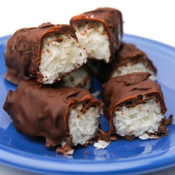 A pile of vegan Mounds bars that have been cut in half on a blue plate.