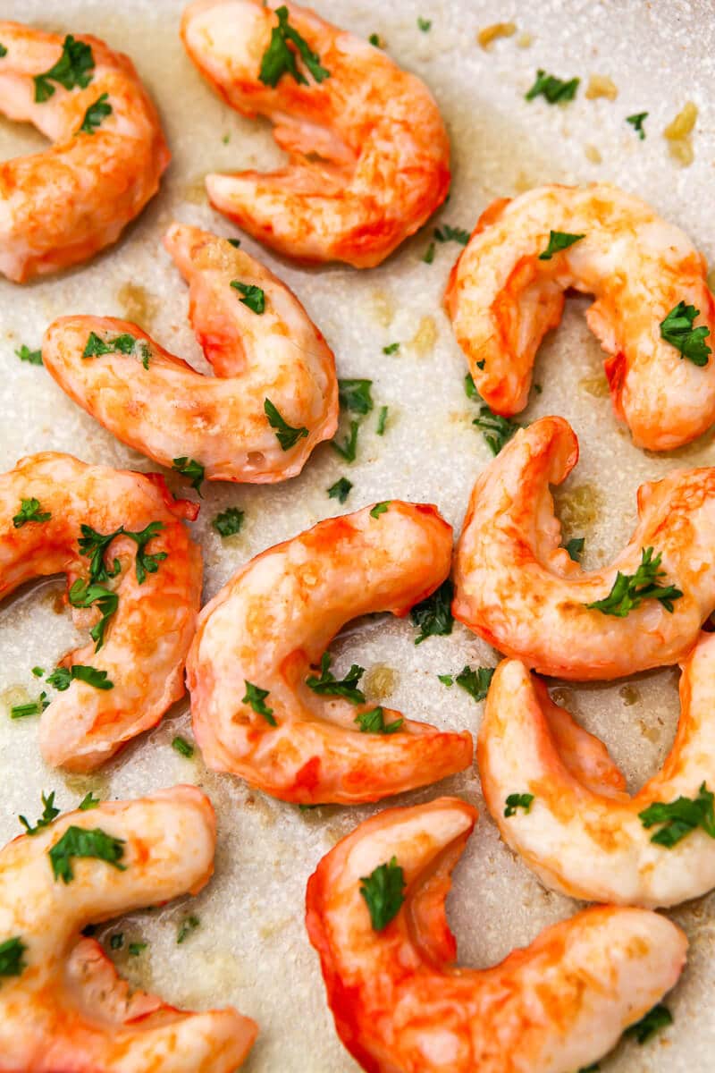 Vegan shrimp sauted in a pan with butter and garlic and sprinkled with fresh parsley.
