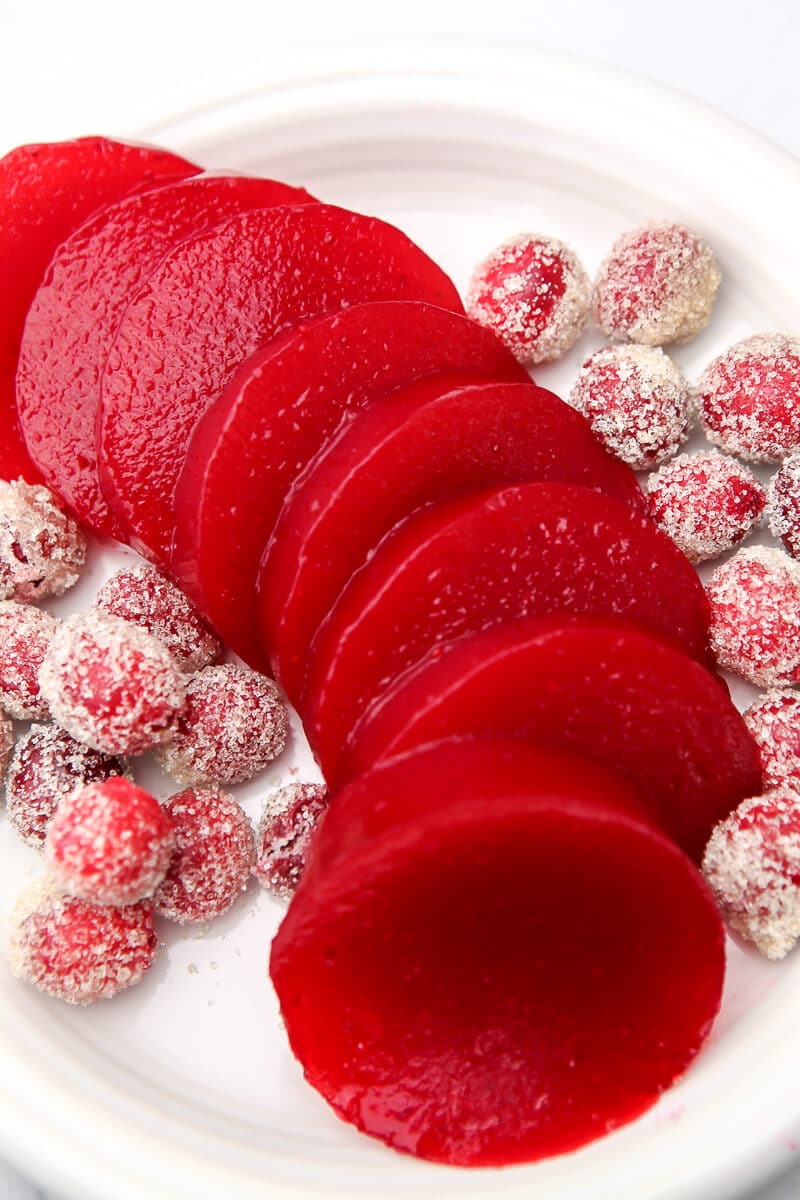 A top view of sliced jellied cranberry sauce with sugared cranberries on the side.