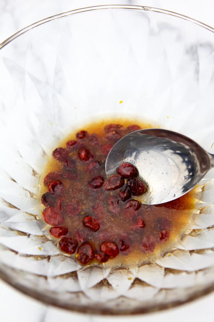 A salad bowl with maple balsamic vinaigrette dressing and dried cranberries.