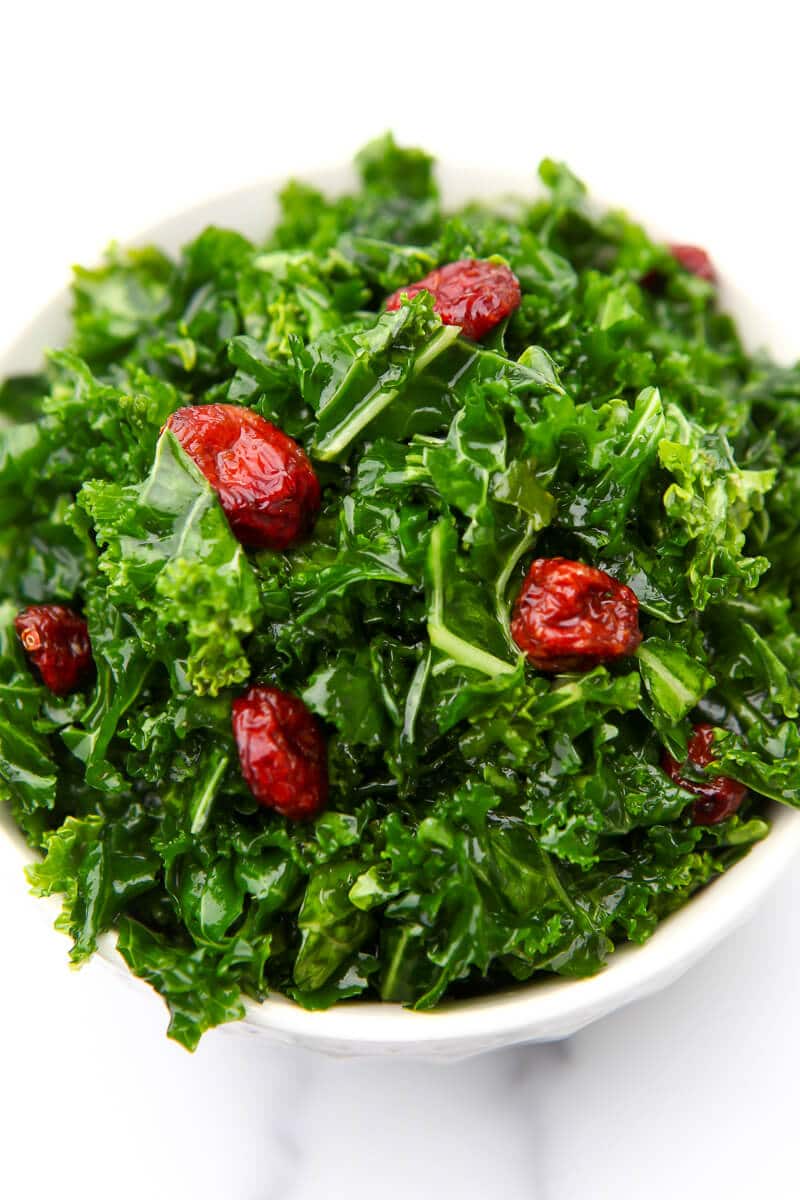 A top view of a kale salad with dried cranberries.