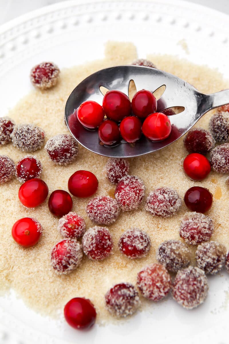 Dropping cranberries onto a plate of sugar to make sugared cranberries.