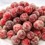 A pile of sugared cranberries on a white plate.
