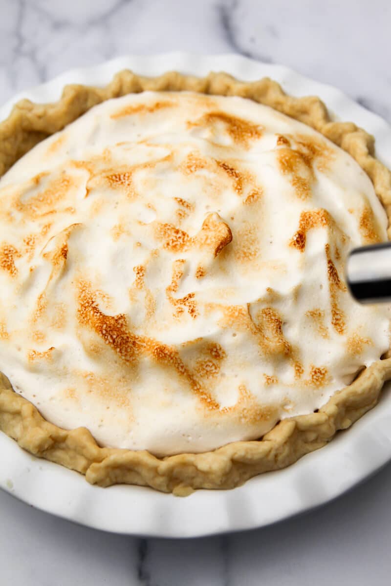 A vegan meringue pie being toasted with a kitchen torch.