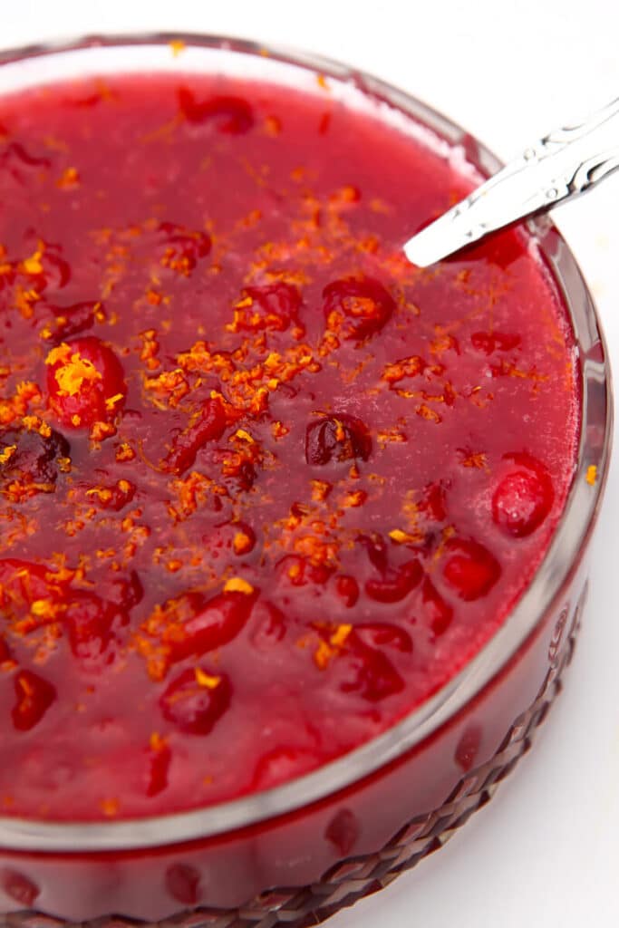 A top view of a bowl of vegan cranberry sauce with spoon in it.