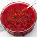 A glass bowl filled with vegan cranberry sauce with orange zest on top.