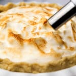 A pie with vegan meringue being toasted with a kitchen torch.