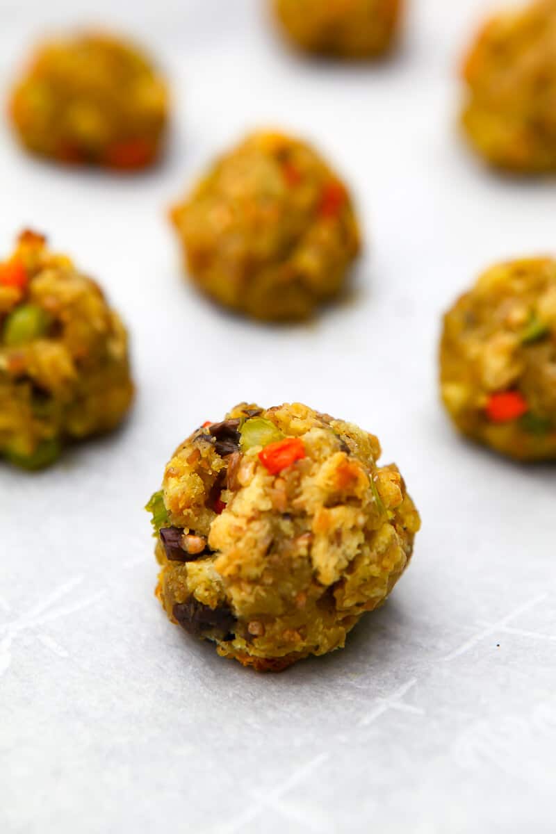 A close up of vegan stuffing balls on a cookie sheet with parchment paper under them.