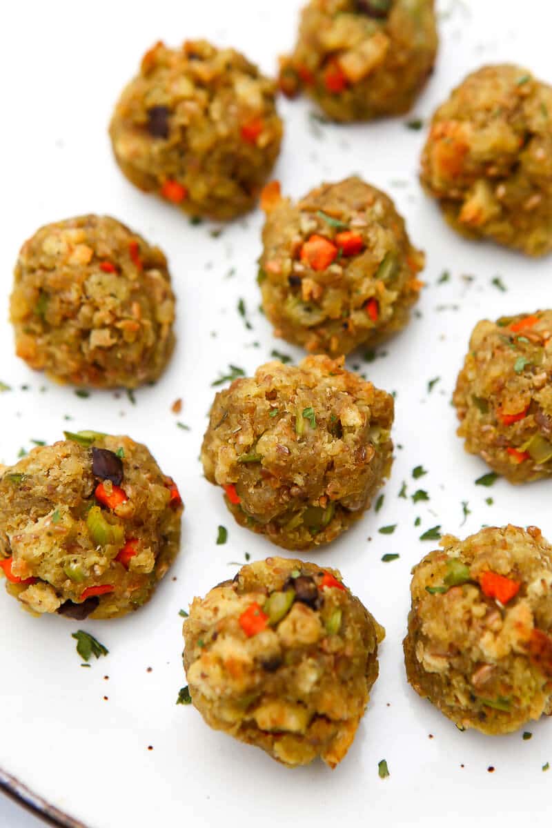 Vegan stuffing balls on a white plate with some parsley sprinkled on them.