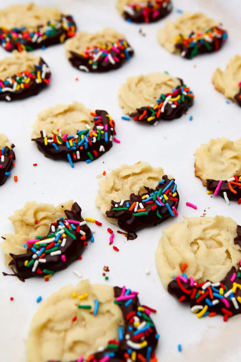 Vegan butter cookies with the sides dipped in chocolate and covered with sprinkles. 