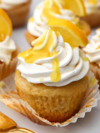 A vegan lemon cupcake with lemon curd drizzled on top.