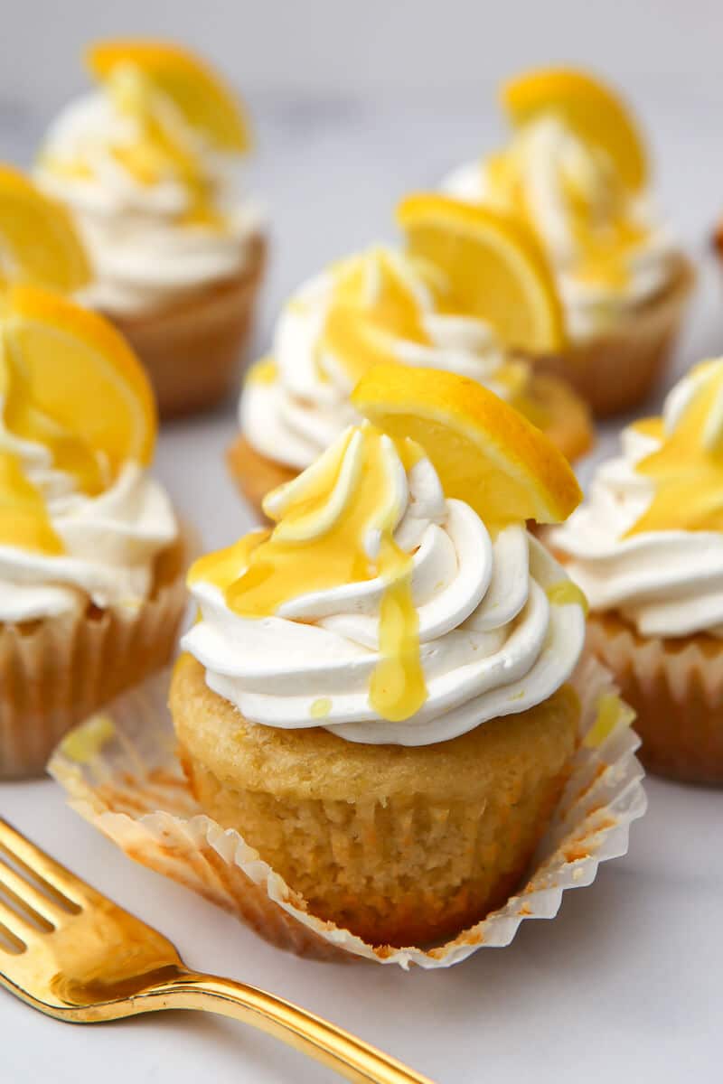 Vegan lemon cupcakes with lemon frosting and drizzled with lemon curd and topped with a lemon slice.