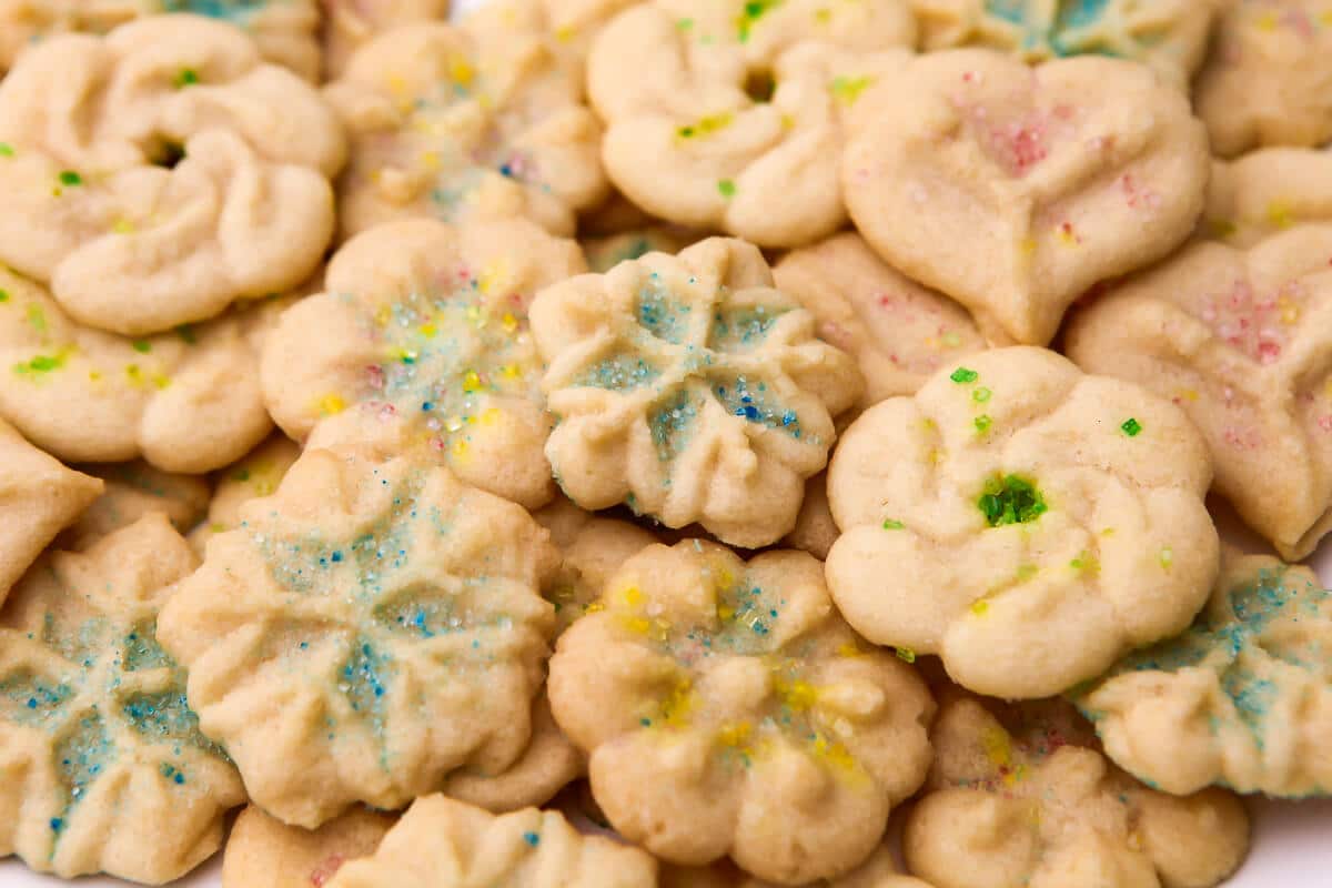 A stack of vegan spritz cookies decorated with sanding sugar in different colors.