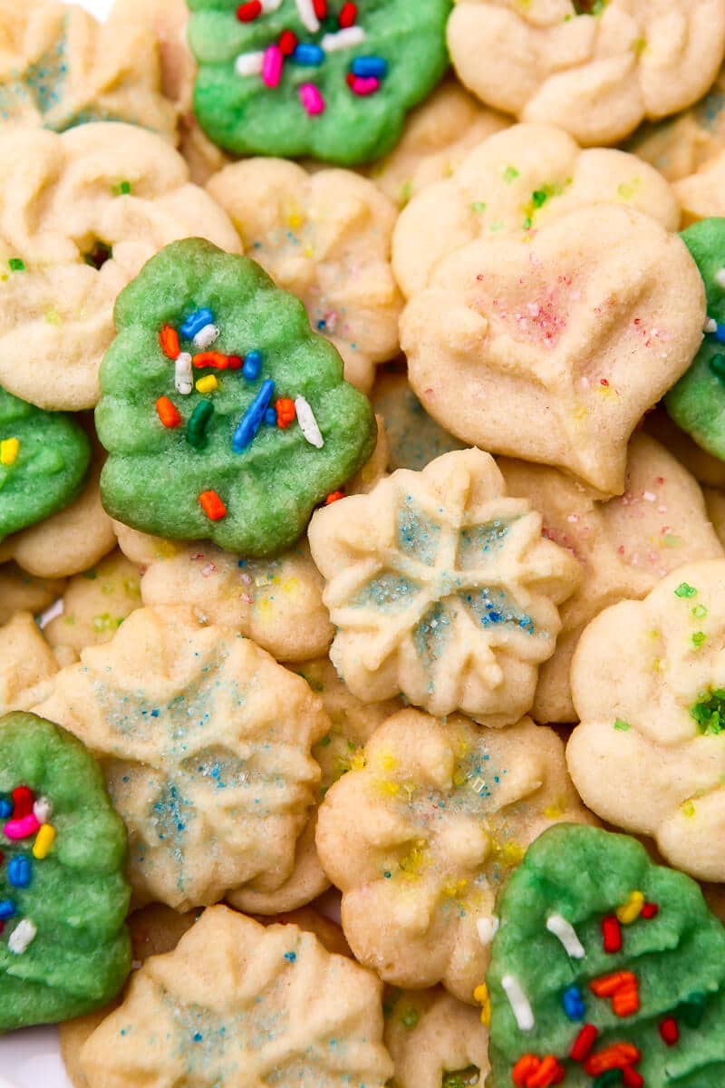 A close up of vegan spritz cookies in the shape of snowflakes, wreaths, and christmas trees.