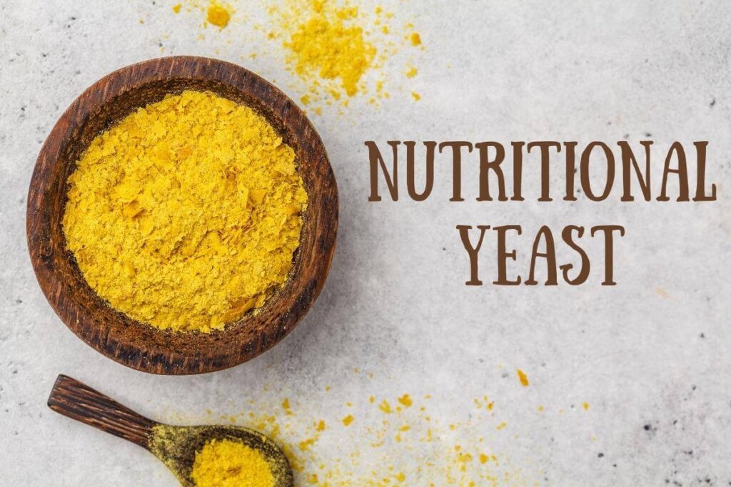 A bowl of nutritional yeast with a spoonful on the side with the word nutritional yeast written on the side.