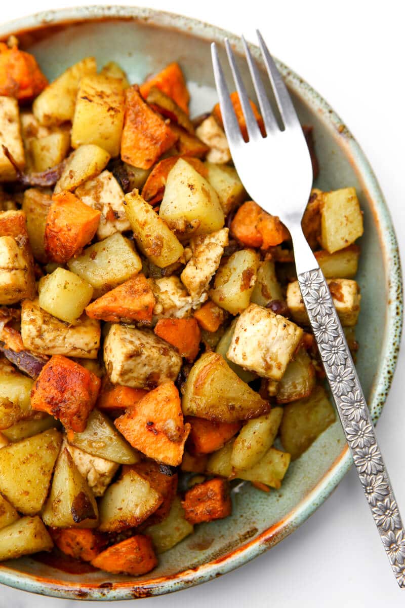 A top view of a plate full of roasted root vegetables on a plate with a fork on the side.