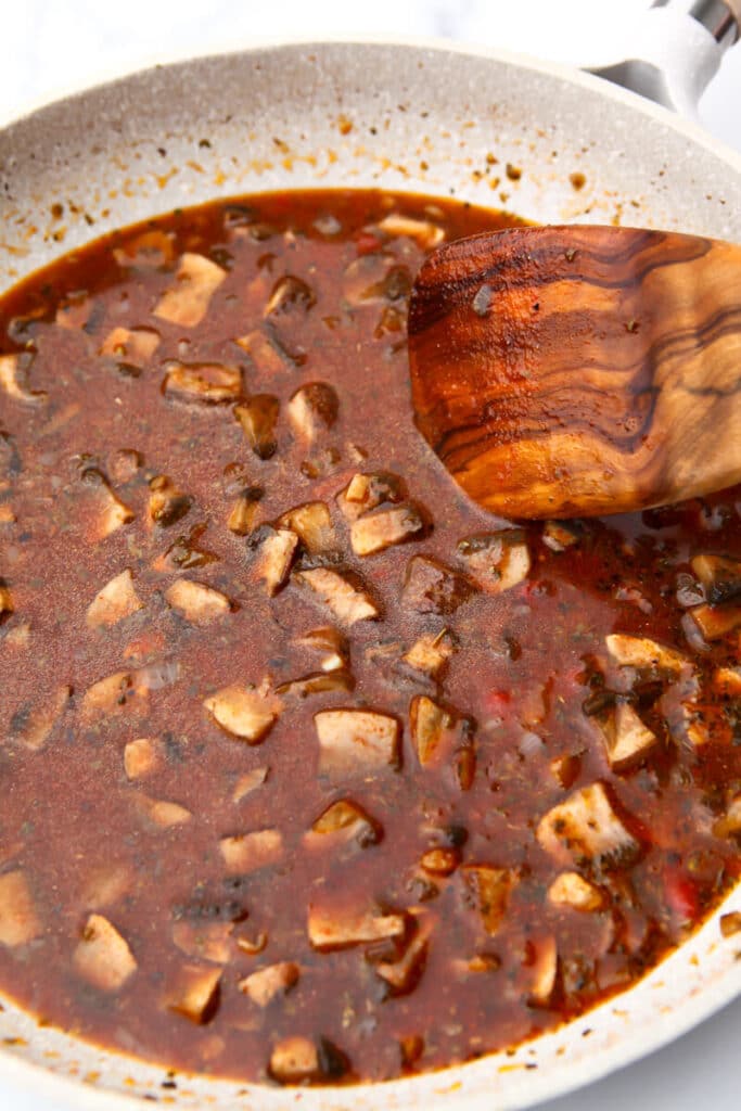 Onions and mushrooms sauteed in a frying pan with spices, soy sauce, tomato paste, and water added for the flavor base of beef seitan.