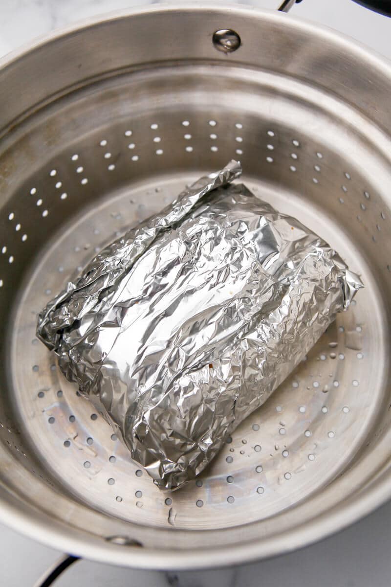 The vegan beef roasted wrapped in foil in a steamer basket to cook.