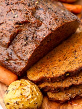 A large piece of vegan beef made from seitan on a cutting board with some slices cut off.