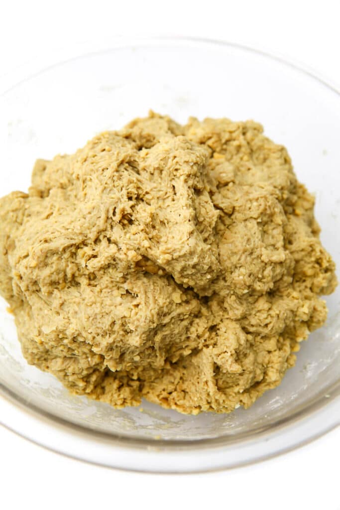 A dough made of chickpeas and vital wheat gluten in a glass bowl.