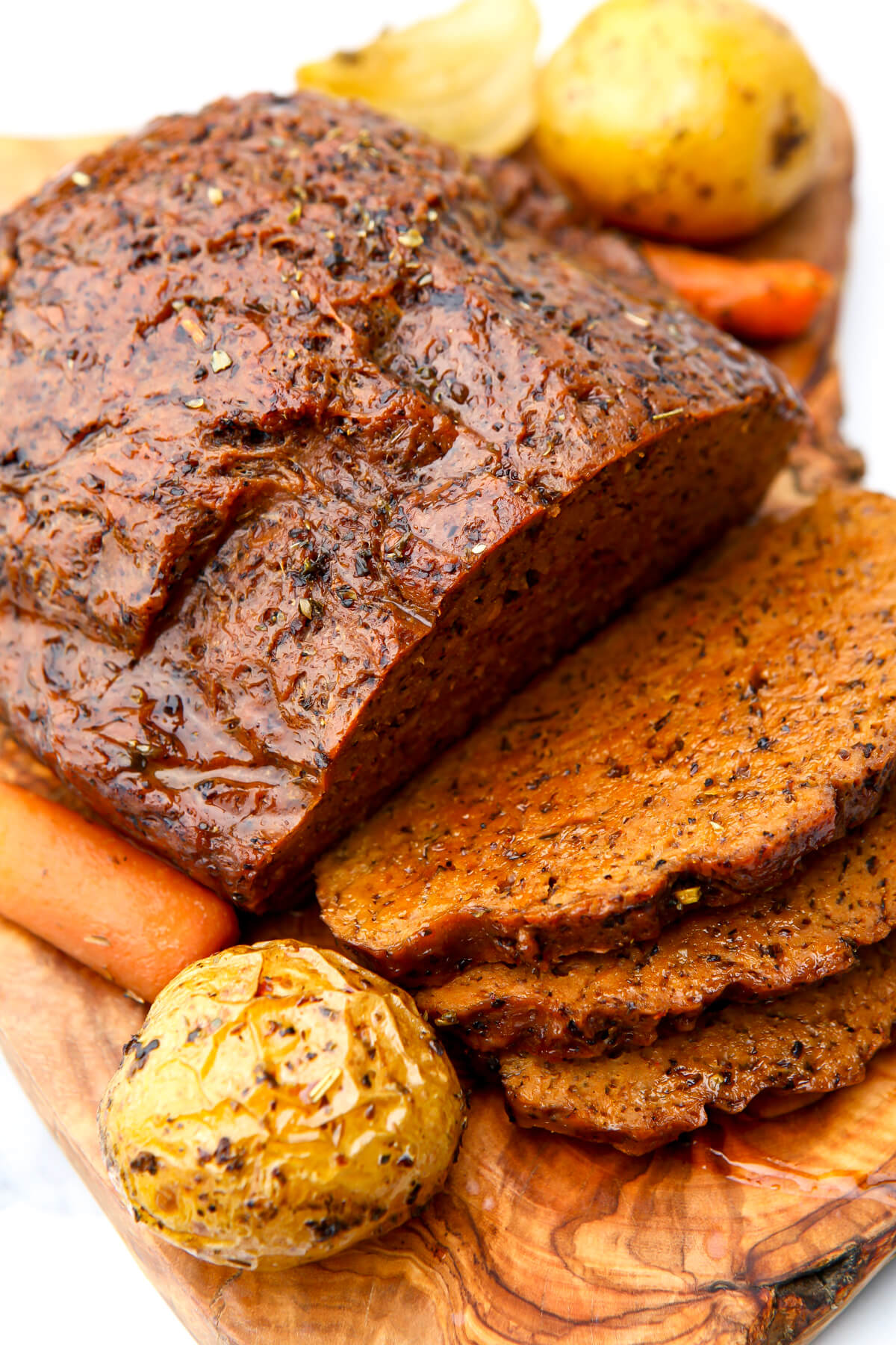 A vegan pot roast on a cutting board cut into slices.