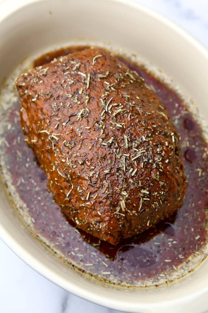 Vegan roast beef with oil and seasonings poured over top before it is roasted.