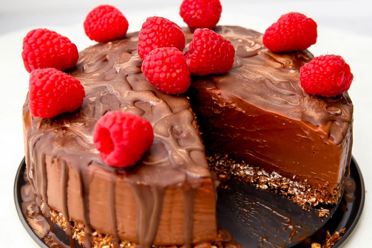 A vegan chocolate cheesecake with raspberries on top.