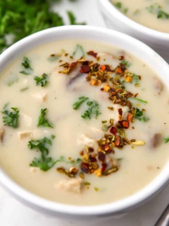 A bowl of vegan cream of chicken soup with a spoon on the side.