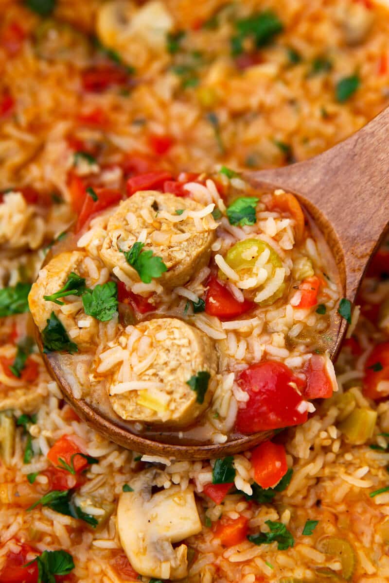 A close up of a wooden ladel filled with vegan jambalaya.